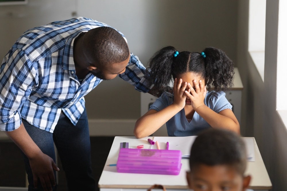 Spotting depression- sad girl comforted by teacher in class