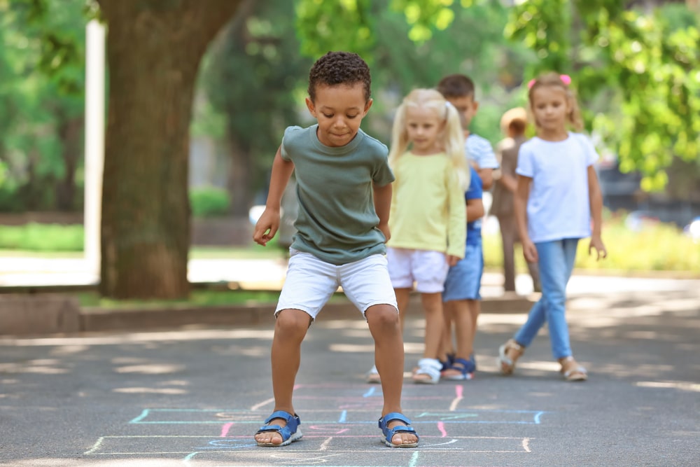 Negative and positive number activities children playing hopscotch outdoors